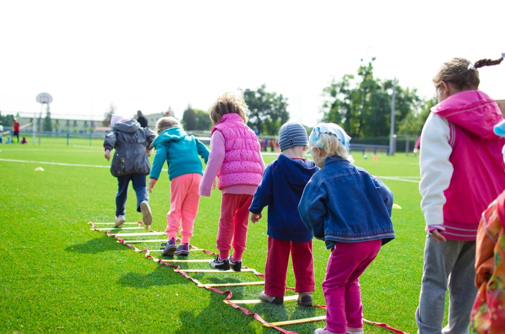 Children jumping on green grass.